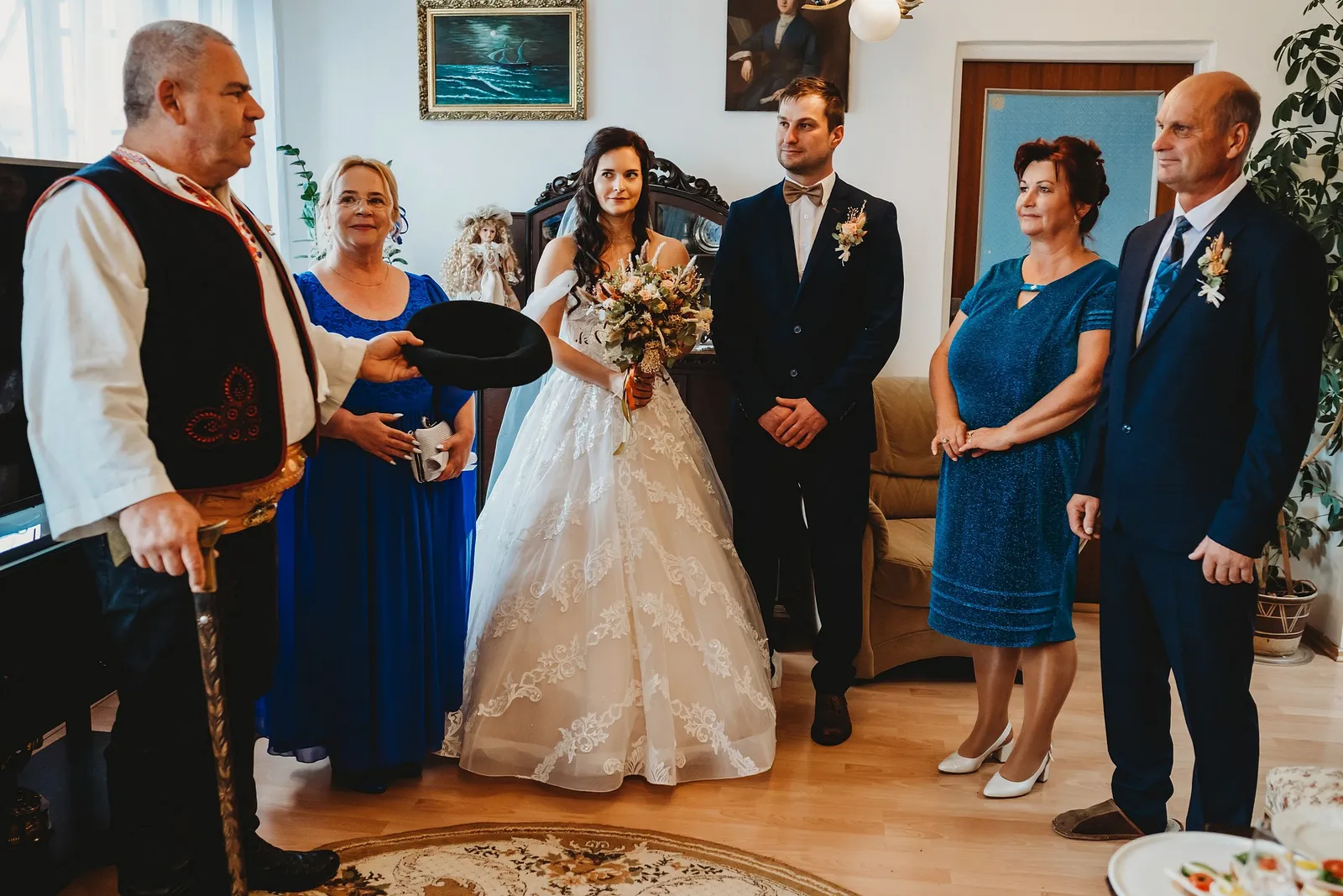 Starejší vo vyšívanej veste s klobúkom a palicou hovorí odobierku pred mladomanželmi a rodičmi – svadba Majka a Marek, Hotel Máj, Liptovský Ján