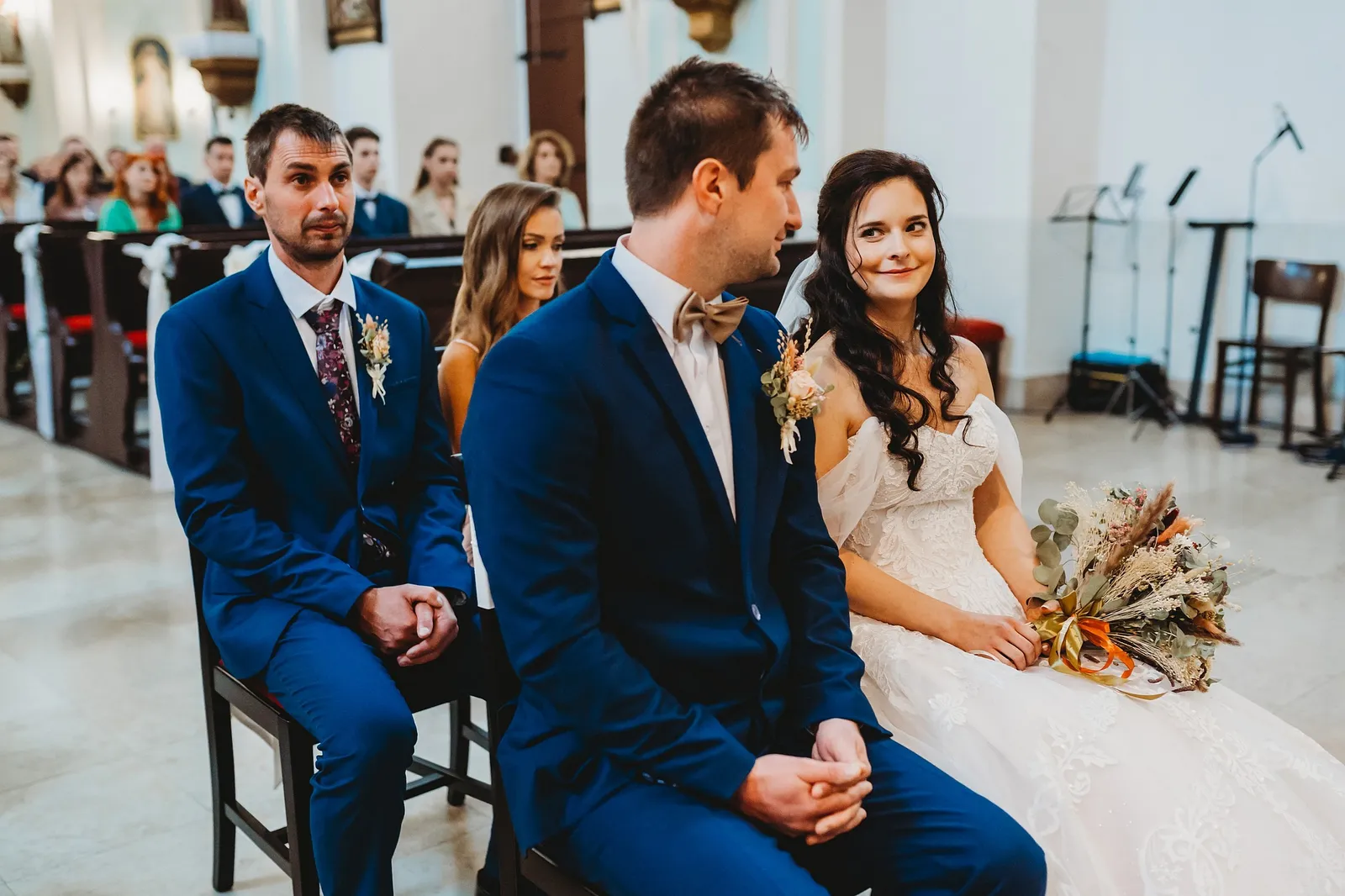 Nevesta, ženích, svedok a svedkyňa sedia počas obradu v kostole, nevesta drží kyticu v lone – svadba Majka a Marek, Hotel Máj, Liptovský Ján