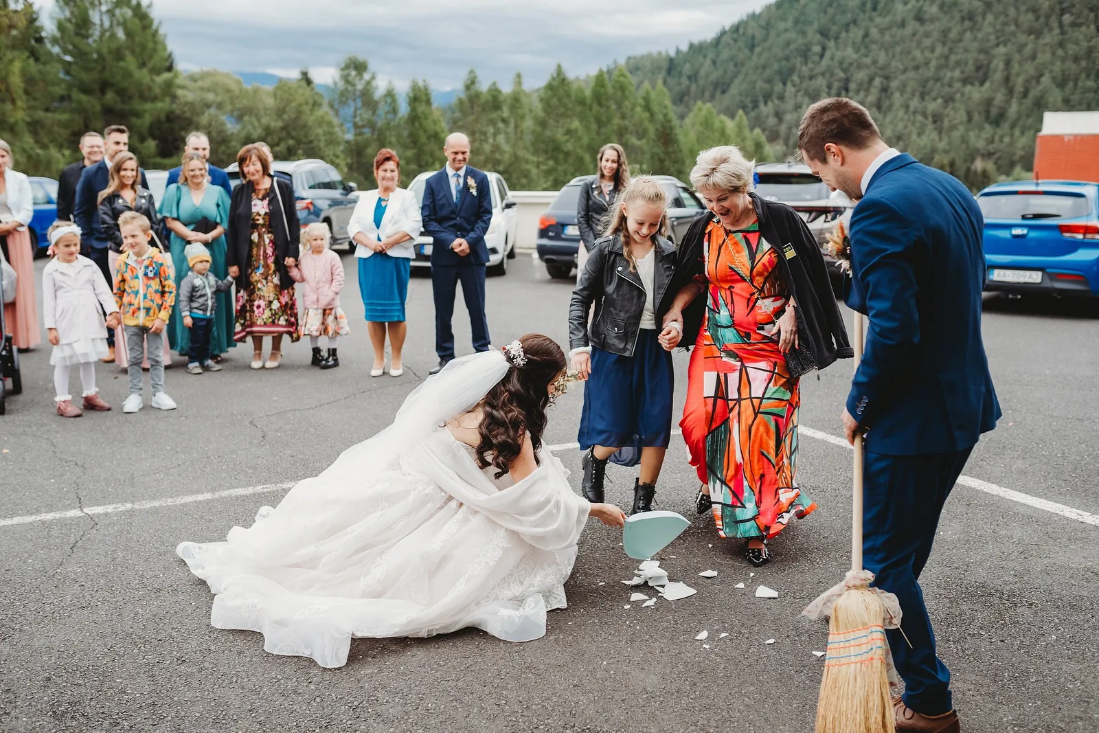 Nevesta v kľaku zametá rozbitý tanier na parkovisku, ženích drží metlu a hostia sa smejú – svadba Majka a Marek, Hotel Máj, Liptovský Ján