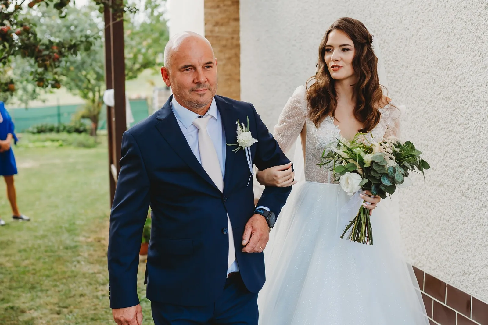 Nevesta s kyticou bielych ruží a eukalyptu kráča pod pazuchou s mužom v tmavomodrom obleku – svadba Peťka a Peťo, Stodola Liptovský dvor
