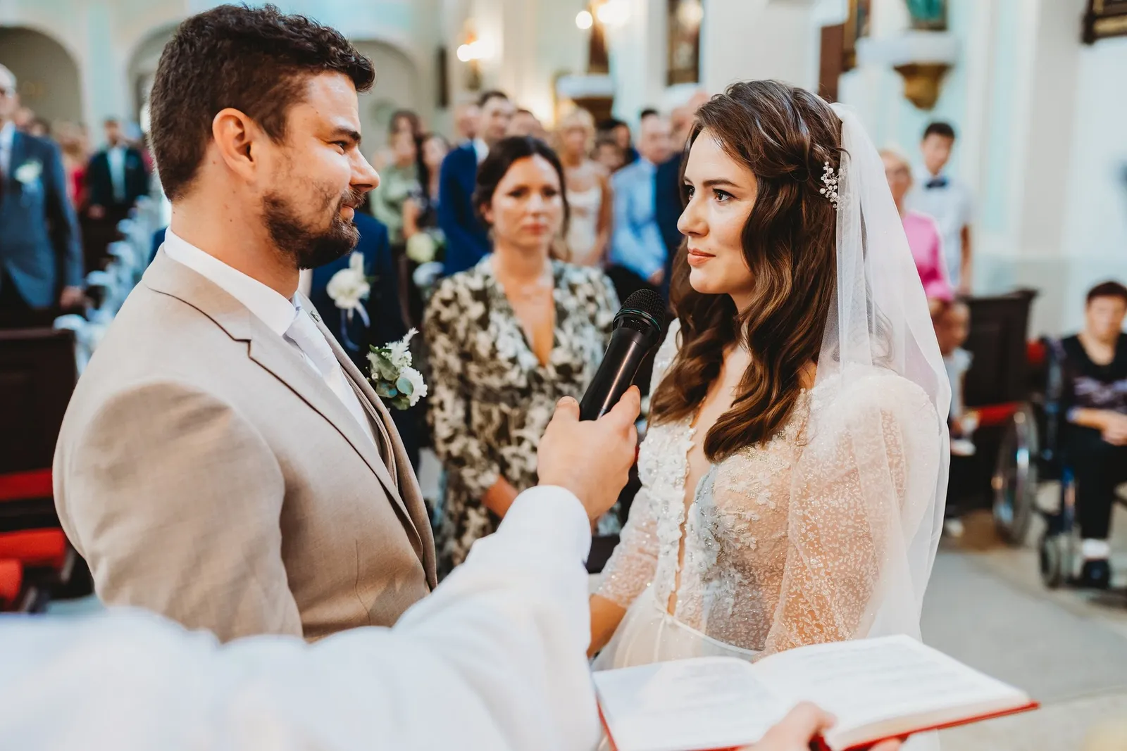 Nevesta a ženích si hľadia do očí pri sľube, kňaz drží mikrofón a obradnú knihu – svadba Peťka a Peťo, Stodola Liptovský dvor