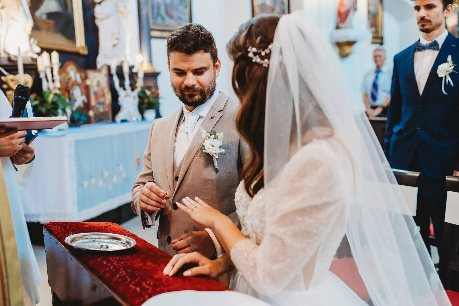 Ženích berie obrúčku z tácky na červenom zamate, nevesta mu podáva ruku – svadba Peťka a Peťo, Stodola Liptovský dvor
