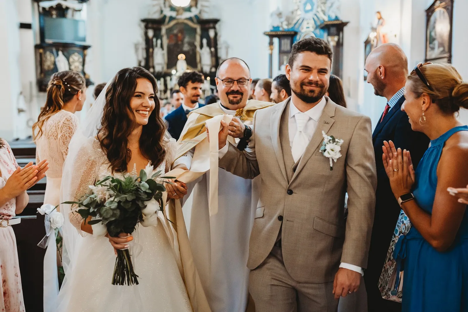 Kňaz vedie novomanželov za štólu ovinutú okolo ich rúk, svadobčania tlieskajú – svadba Peťka a Peťo, Stodola Liptovský dvor