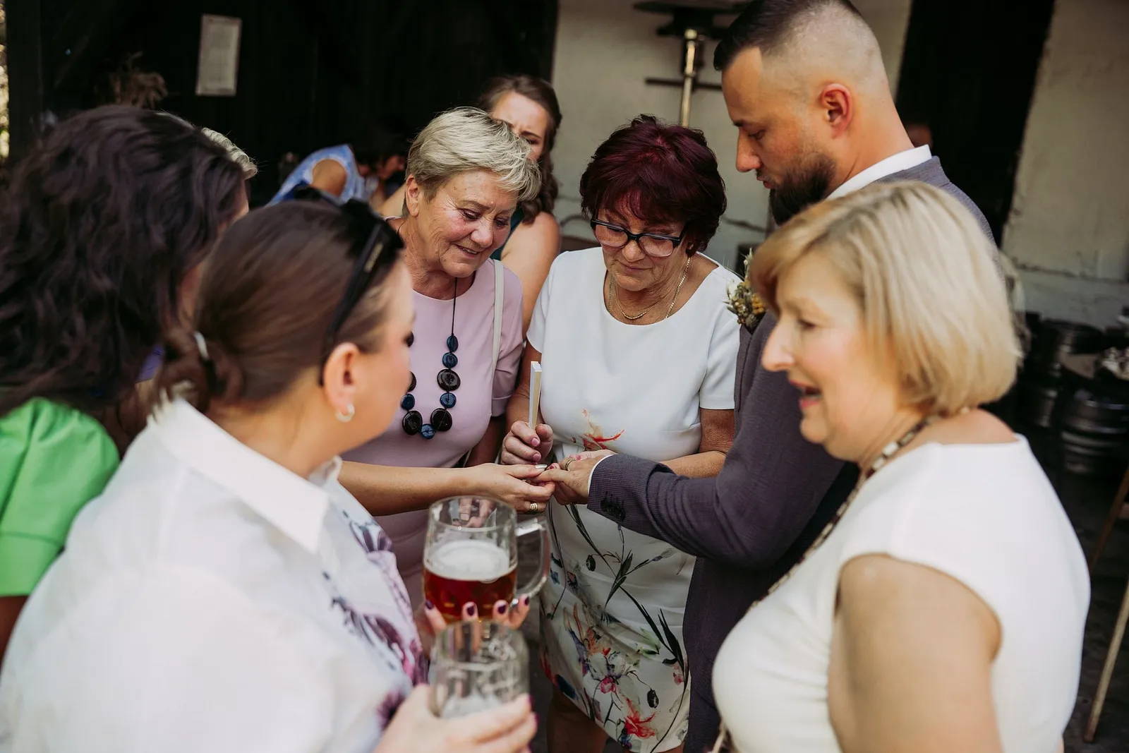 Ženích ukazuje obrúčku hostiam, ktoré si ju so záujmom prezerajú pri pive – svadba Ivka a Ondro, Humno Trnka, Záskov