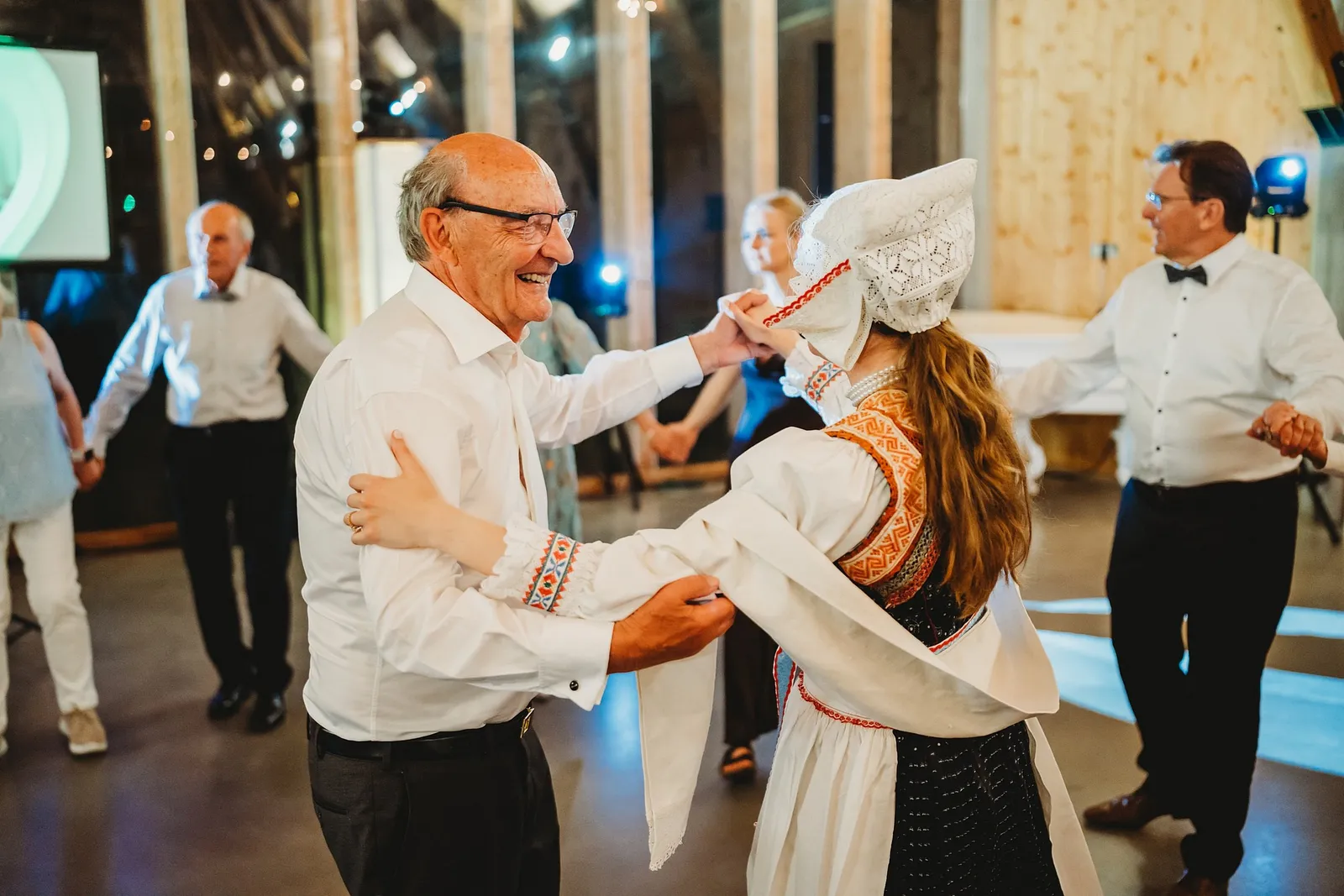 Usmiaty pán v okuliaroch tancuje s nevestou v čepci a vyšívanom kroji – svadba Sandra a Sebastian, Stodola Gréta