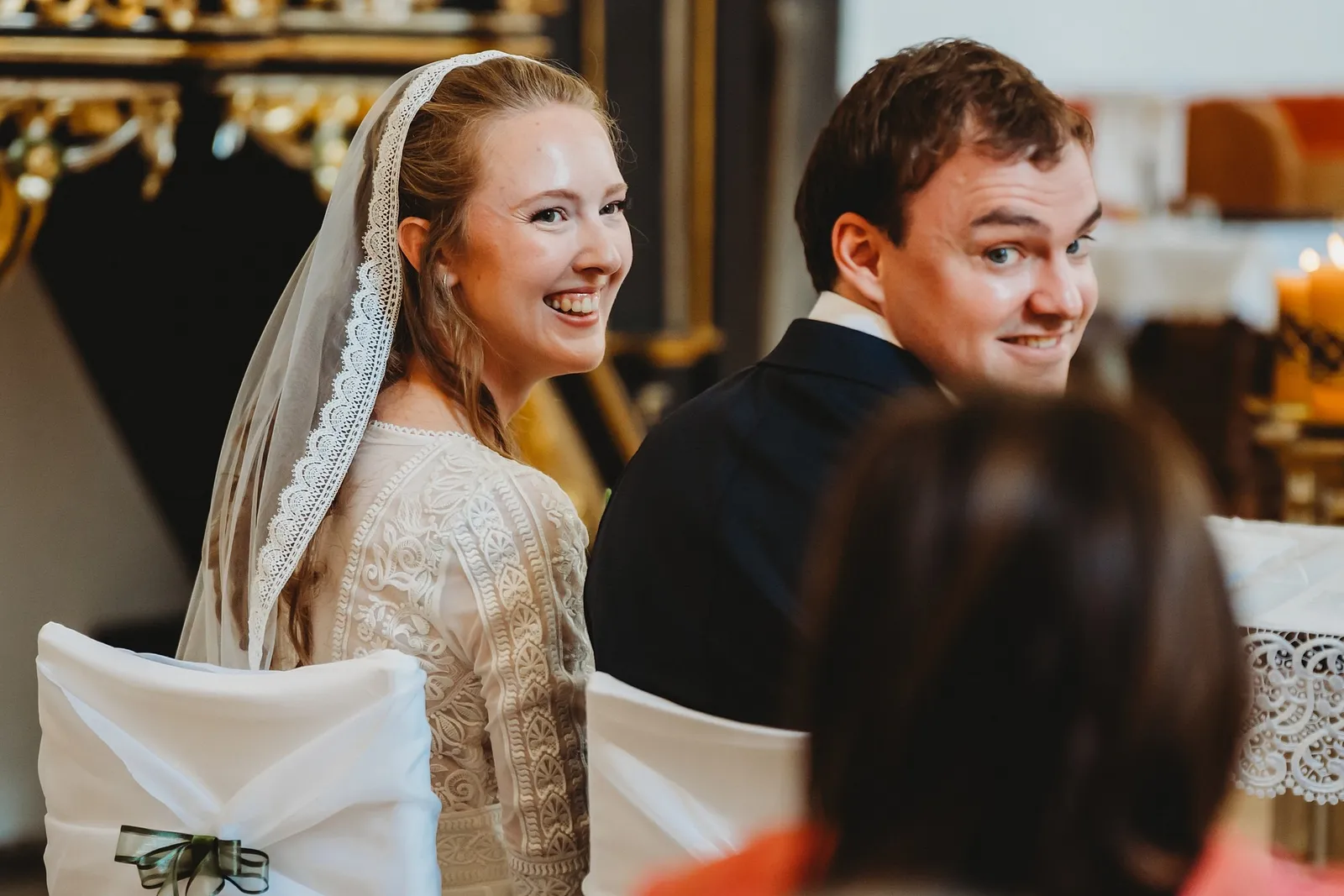 Nevesta v závoji a ženích sa počas obradu s úsmevom obzerajú cez plece – svadba Sandra a Sebastian, Stodola Gréta
