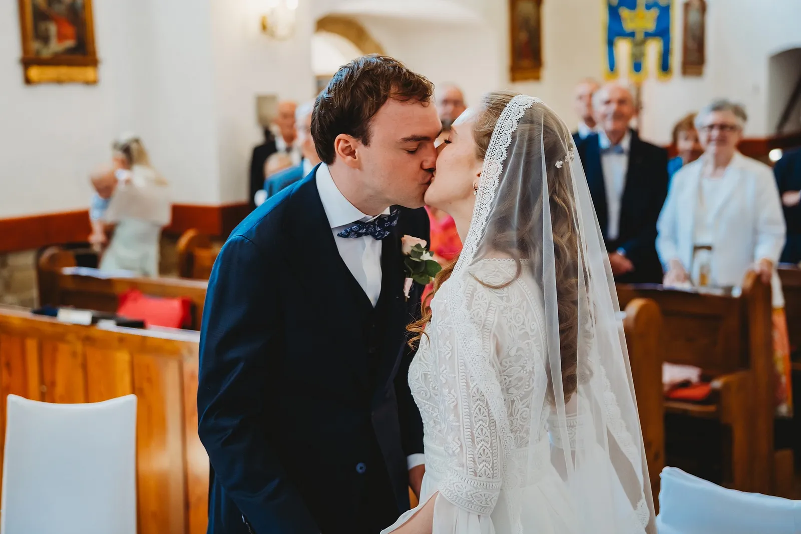 Novomanželia sa bozkávajú pri oltári v kostole, nevesta v čipkovom závoji – svadba Sandra a Sebastian, Stodola Gréta