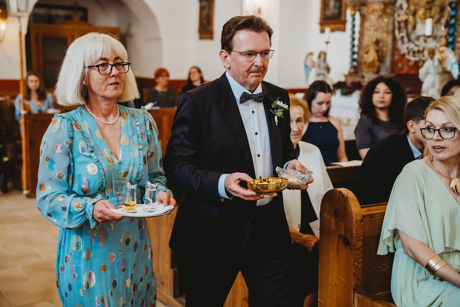 Rodičia prinášajú k oltáru kalich a podnos s krčahmi počas svadobnej omše – svadba Sandra a Sebastian, Stodola Gréta