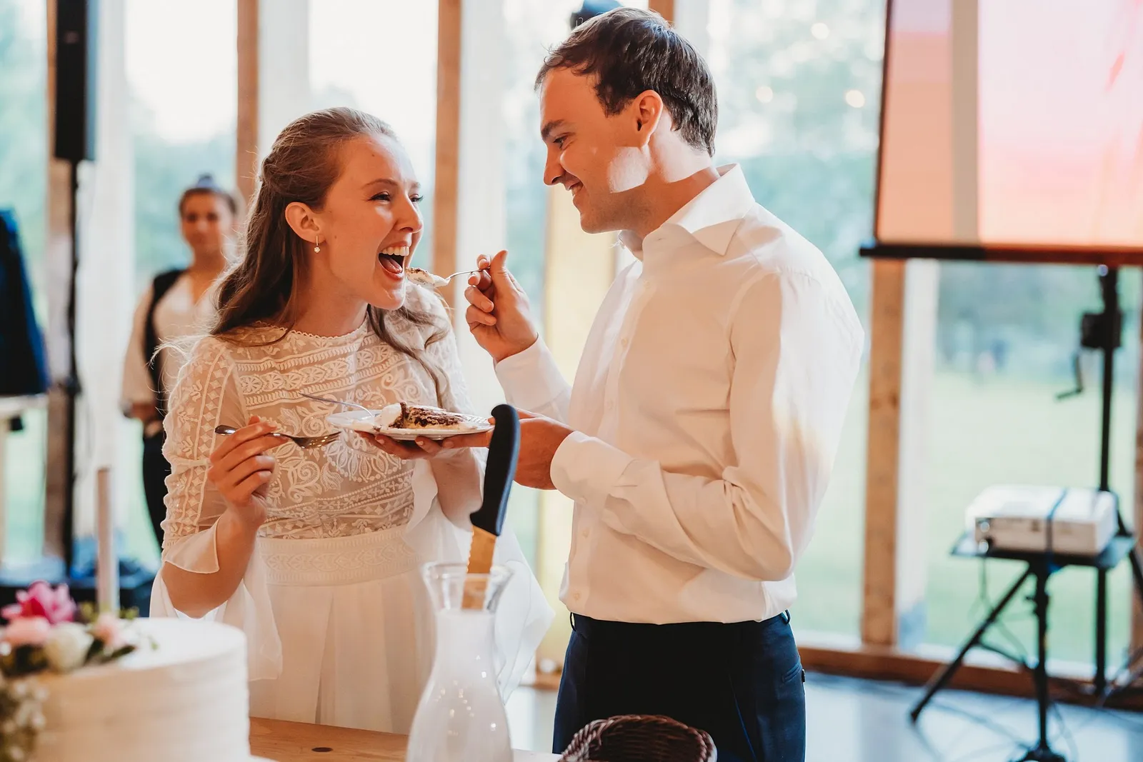 Nevesta sa smeje a ženích s krémom na líci ju kŕmi kúskom torty – svadba Sandra a Sebastian, Stodola Gréta