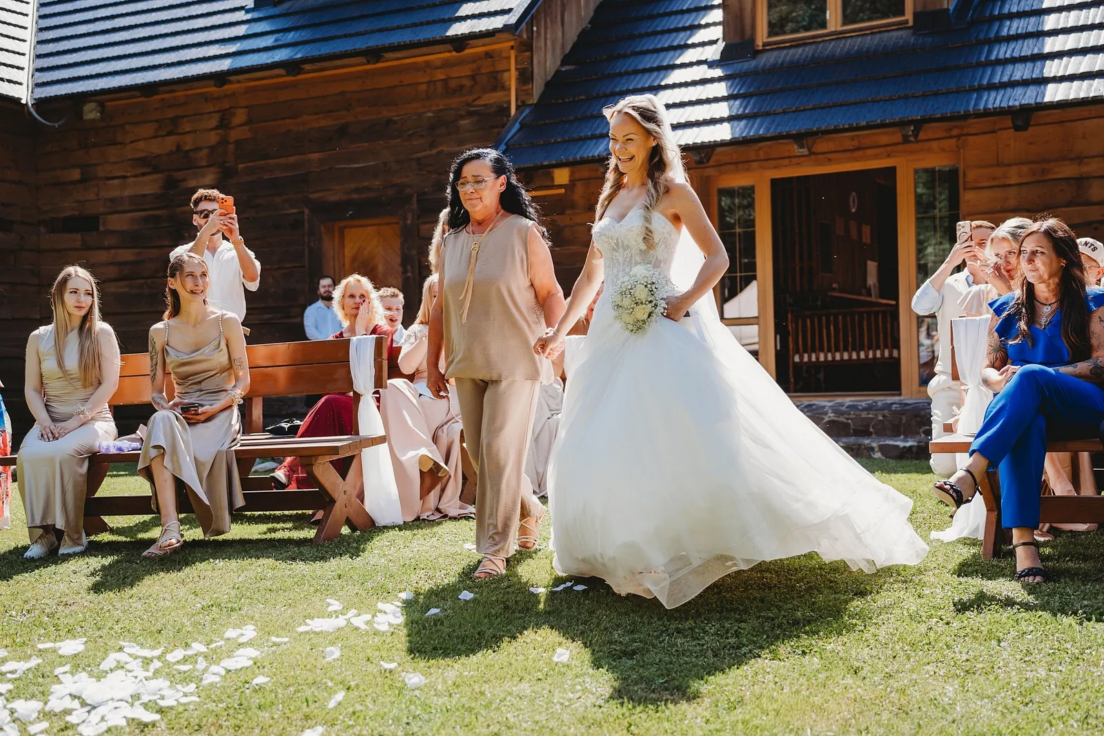 Usmiata nevesta v čelenke prichádza s mamou k obradu, hostia ju fotia – svadba Simonka a Nuri, Stodola Liptovský dvor