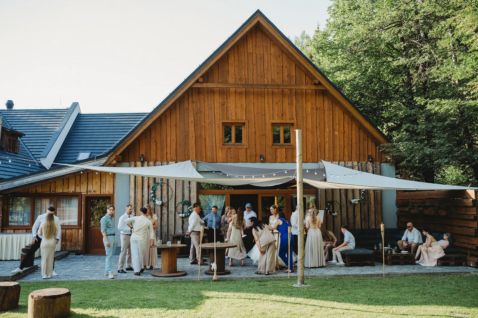 Hostia na terase pred drevenou stodolou pod plachtami na tienenie – svadba Simonka a Nuri, Stodola Liptovský dvor