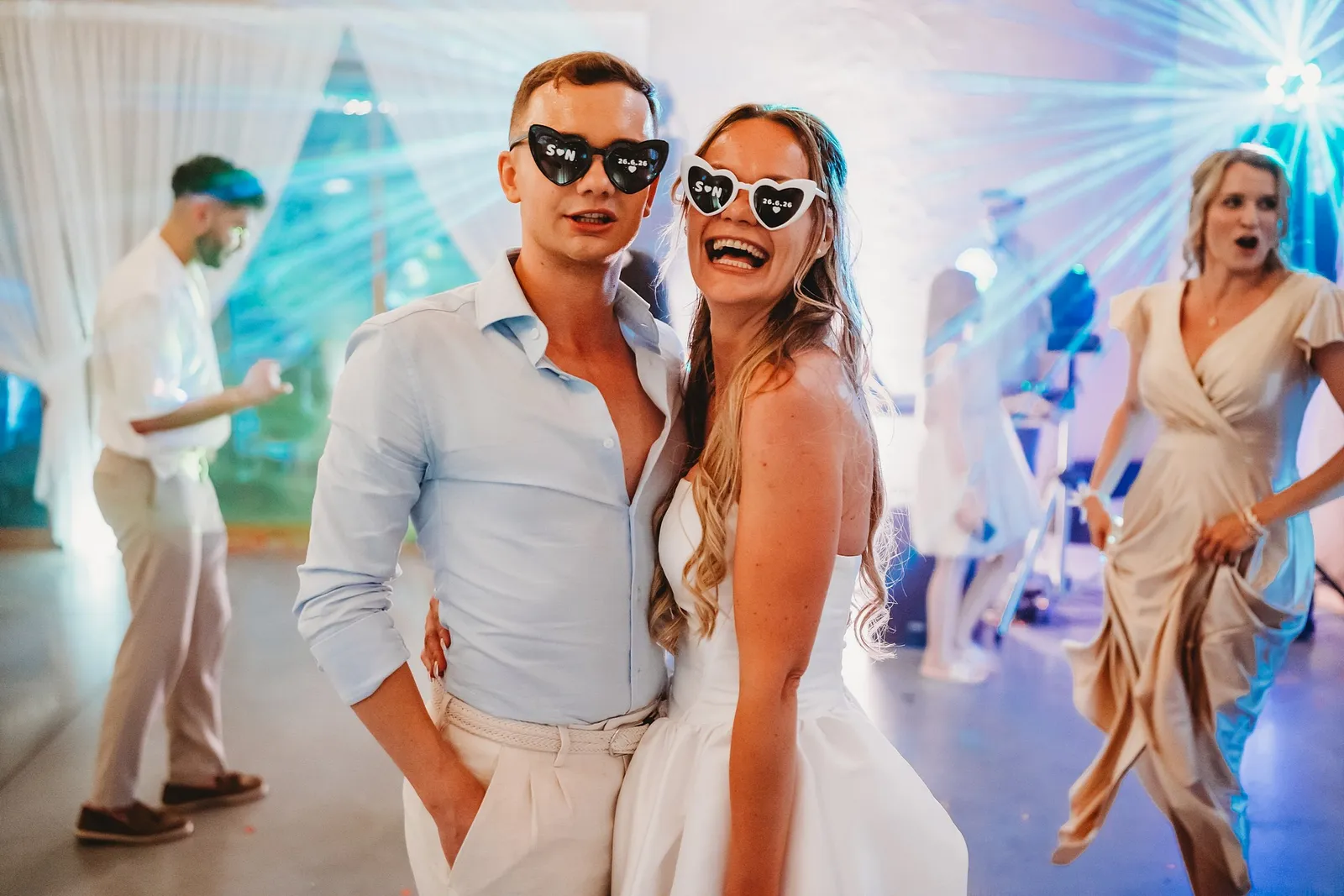 Nevesta a hosť v okuliaroch so srdiečkami pózujú na parkete v modrom svetle – svadba Simonka a Nuri, Stodola Liptovský dvor