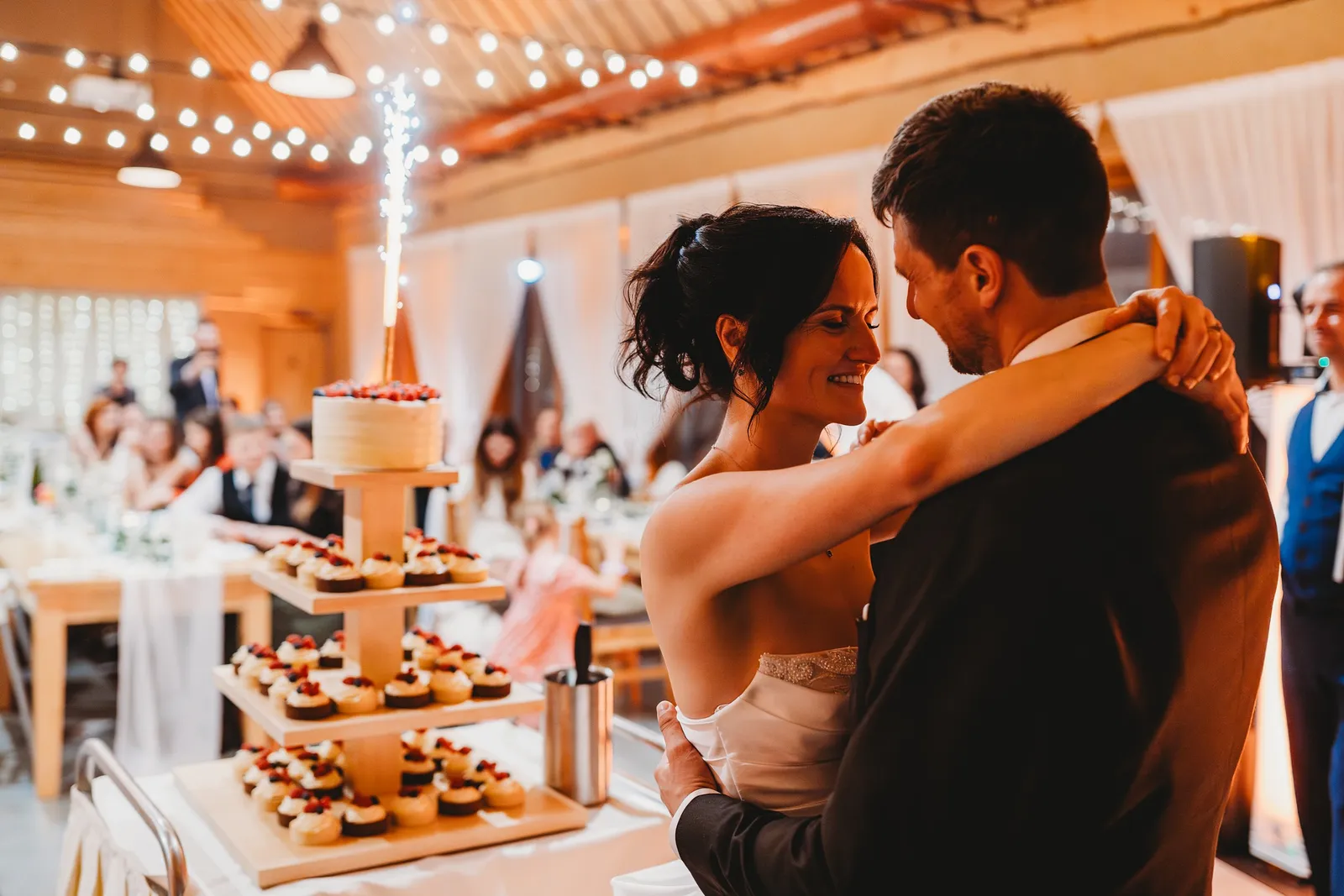 Novomanželia v objatí pri stojane s cupcakes a tortou so žiarivou fontánou – svadba Andrejka a Janko, Stodola Liptovský dvor