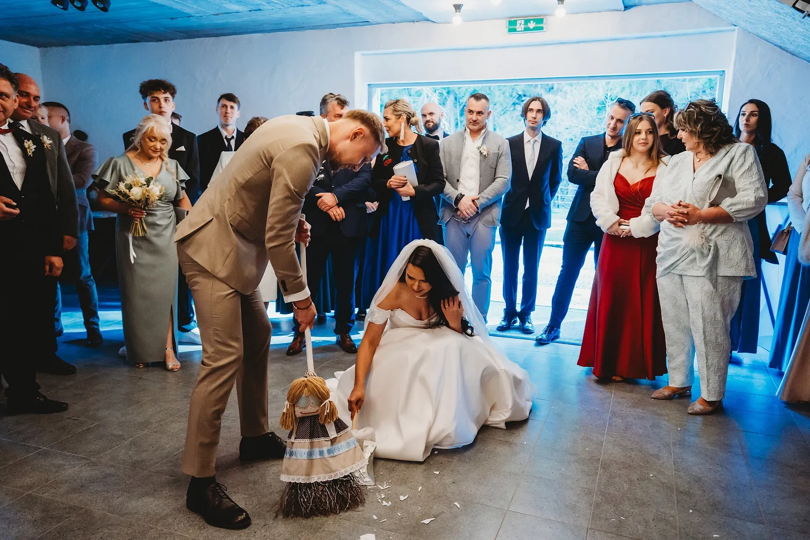 Ženích zametá metlou rozbitý tanier, nevesta kľačí na zemi a hostia sa prizerajú – svadba Denisa a Martin, Stodola na poli