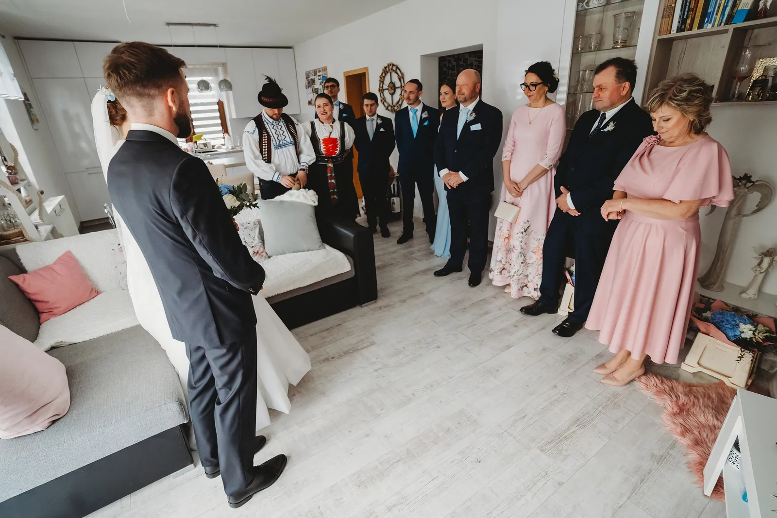 Ženích a nevesta stoja pred rodinou a hosťami v obývačke počas rozlúčky s rodičmi – svadba Natália a Tomáš, Hotel Demänová