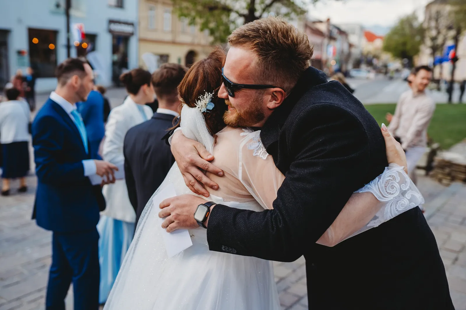 Hosť v slnečných okuliaroch vrúcne objíma nevestu pri gratuláciách pred kostolom – svadba Natália a Tomáš, Hotel Demänová
